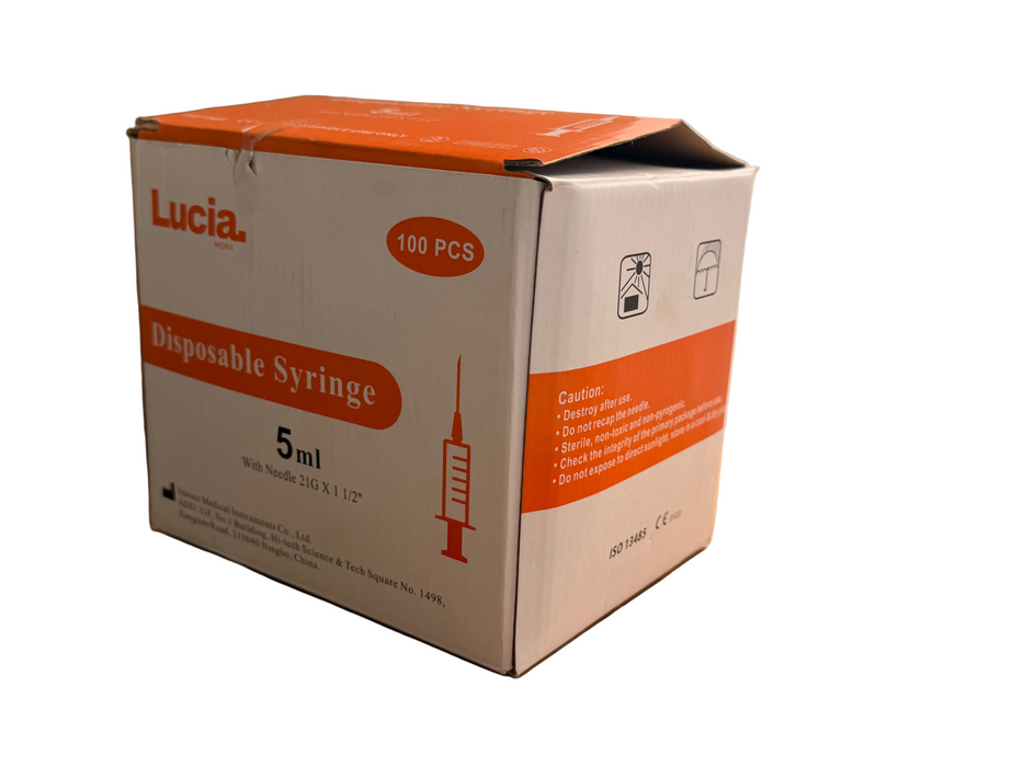 Lucia brand disposable syringe box containing 100 pieces, 5ml size, with orange and white packaging on a cardboard surface.